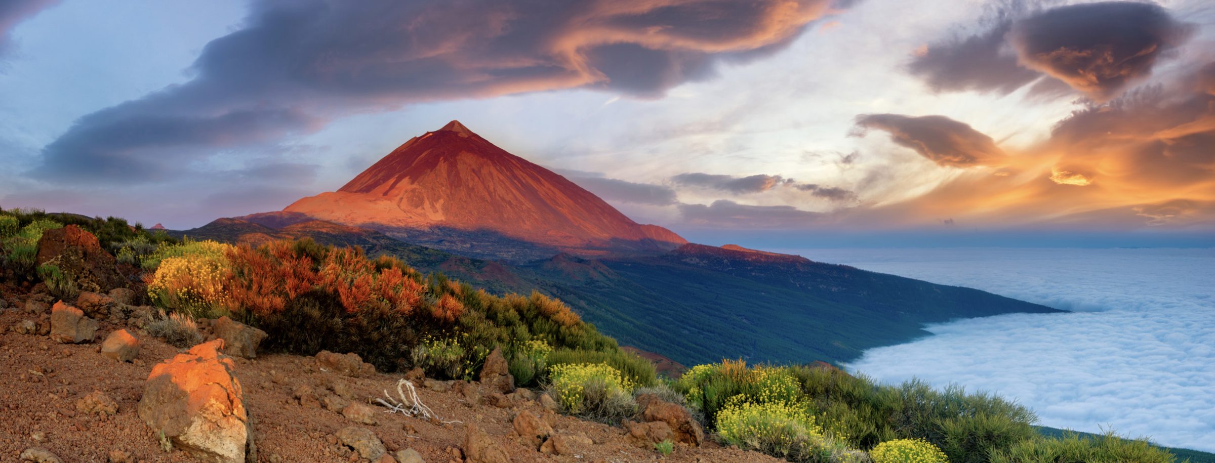 Mount Teide glowing red at sunset above a sea of clouds